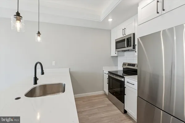 a kitchen with stainless steel appliances a sink a stove a refrigerator with white cabinets