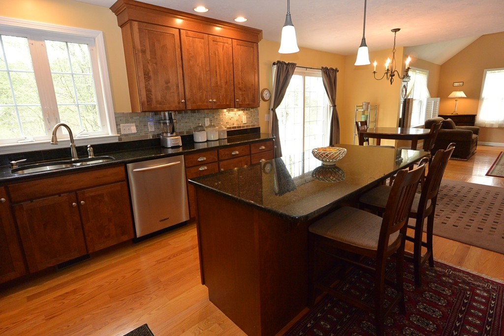 4 Harding Lane Sturbridge, MA 01518 - Photo 3 of 23 a kitchen with wooden cabinets a sink dishwasher a dining table and chairs with wooden floor