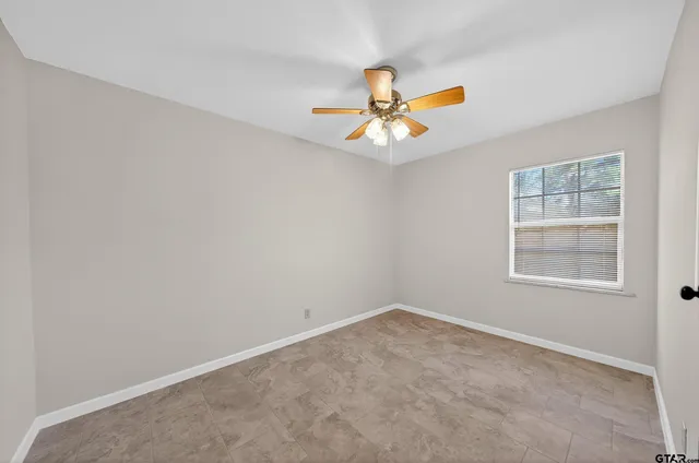 an empty room with a ceiling fan and a window