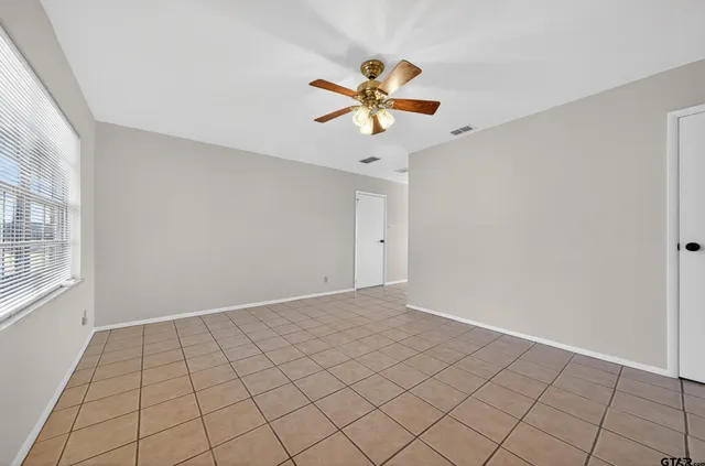 a view of an empty room and a chandelier fan