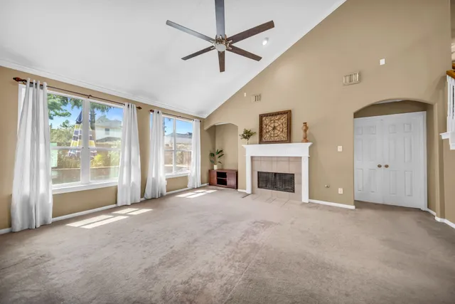 a view of a livingroom with a fireplace a ceiling fan and windows