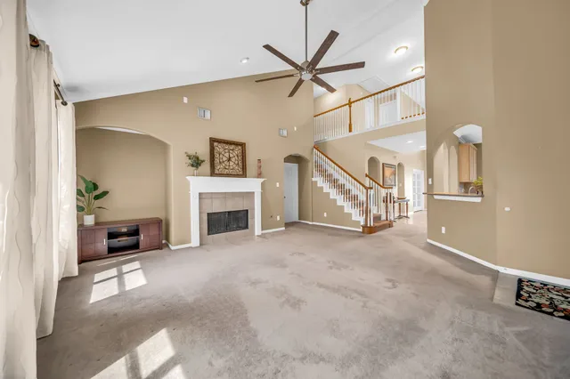 a view of a livingroom with a ceiling fan a fireplace and a window