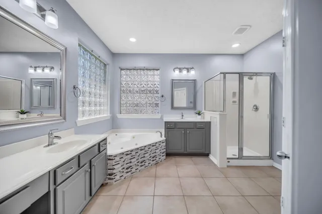 a bathroom with a double vanity sink a large mirror and a bathtub