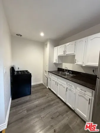 a kitchen with granite countertop white cabinets and black appliances