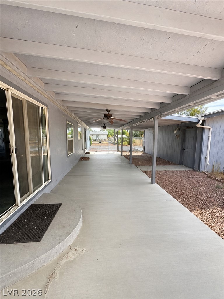5561 Doubletree Road Pahrump, NV 89061 - Photo 15 of 19 A long covered concrete patio features an open beamed ceiling and sliding glass doors.