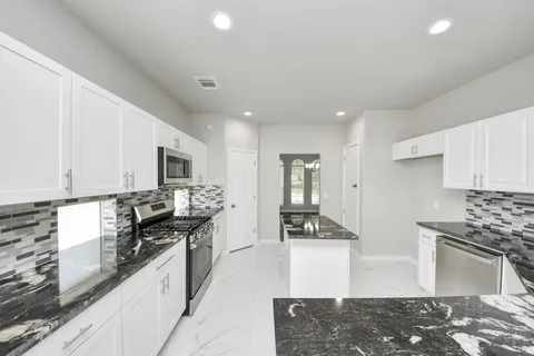 a kitchen with stainless steel appliances kitchen island granite countertop a stove a sink and a refrigerator