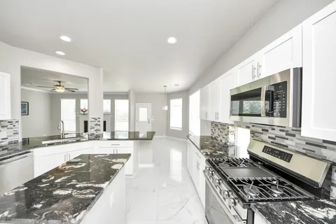 a large kitchen with stainless steel appliances granite countertop a stove and a sink