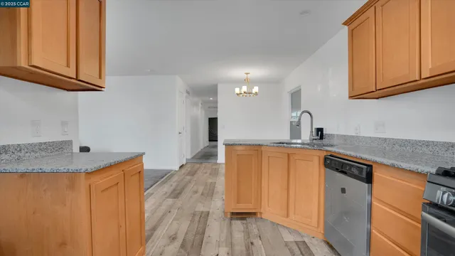 a kitchen with stainless steel appliances granite countertop a sink and dishwasher with wooden floor