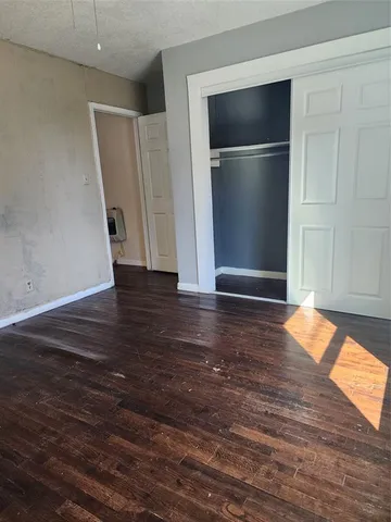 an empty room with wooden floor closet and windows