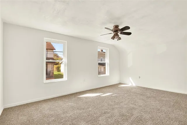 an empty room with windows and a ceiling fan