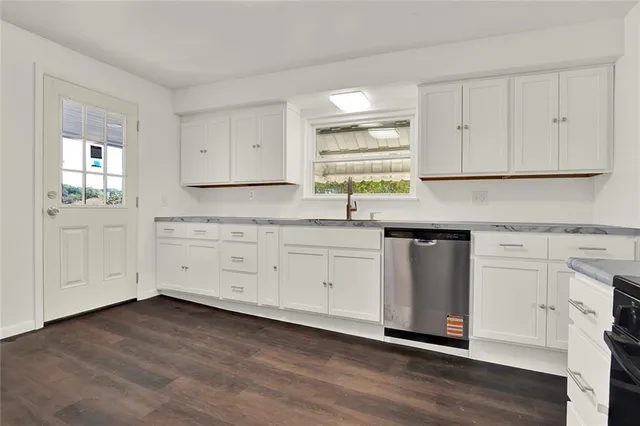 a kitchen with granite countertop white cabinets sink and stainless steel appliances