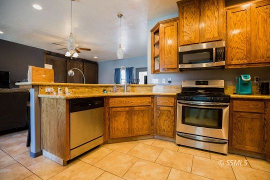 408 Acacia Street Ridgecrest, CA 93555 - Photo 10 of 32 a kitchen with stainless steel appliances granite countertop a stove a microwave and a sink