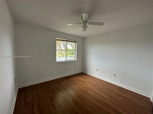 an empty room with wooden floor closet and windows