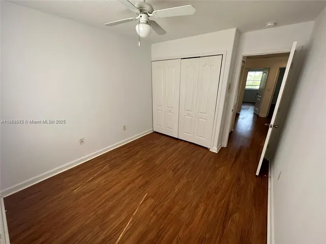 an empty room with wooden floor and fan