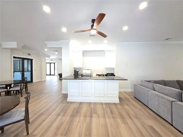 a living room with stainless steel appliances furniture a rug and a kitchen view