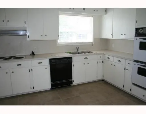 a kitchen with cabinets appliances a sink and a window