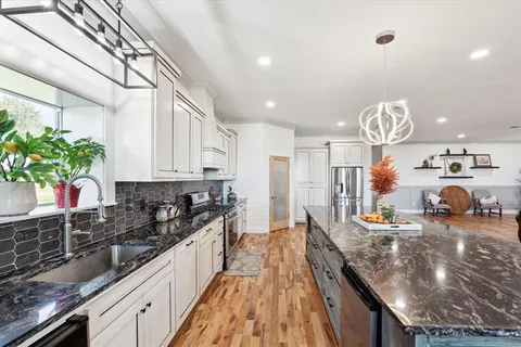 a kitchen with granite countertop a sink a stove and cabinets