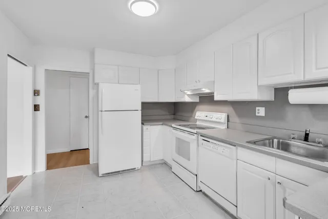 a kitchen with white cabinets and white appliances
