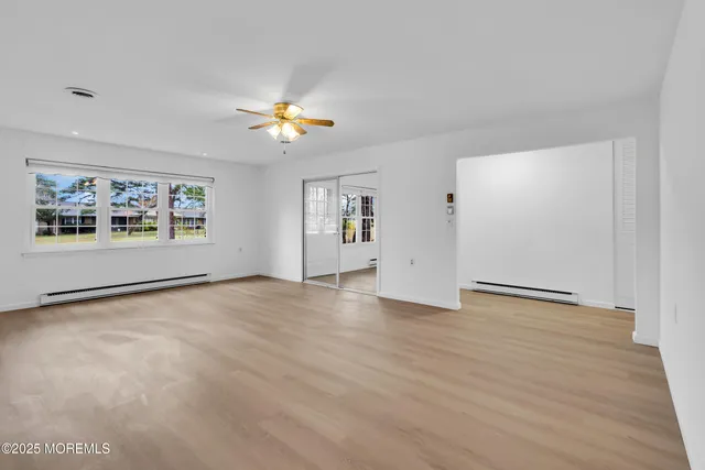 an empty room with windows and ceiling fan