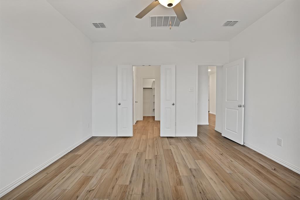 3204 Renaissance Drive Denton, TX 76207 - Photo 13 of 25 Spacious room featuring wood-finish flooring, crisp white walls, and a ceiling fan with integrated lighting