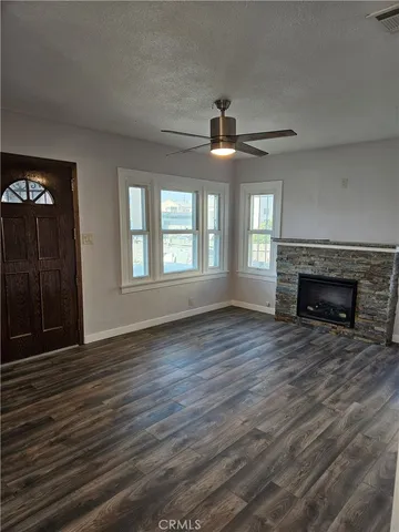 a view of an empty room with wooden floor fireplace and a window