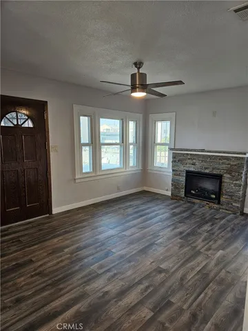 a view of an empty room with wooden floor fireplace and a window