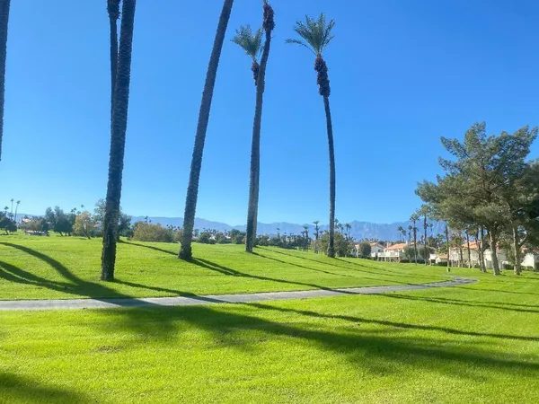 a view of a playground with a big yard and large trees