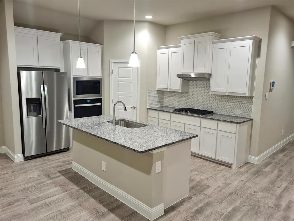 1604 Buzzard Road Denton, TX 76205 - Photo 4 of 22 Kitchen with tasteful backsplash, decorative Pendant lights, sink, white cabinets and appliances with stainless steel finishes.