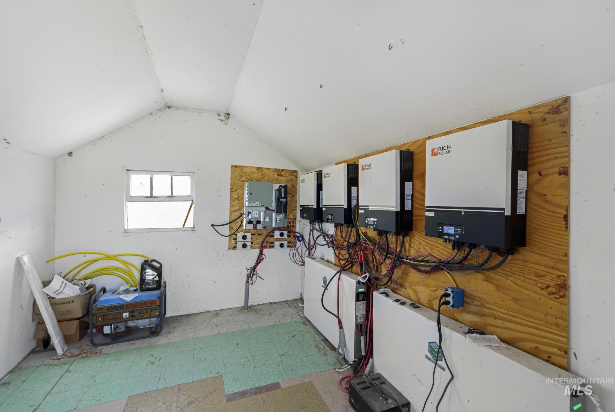 758 Cedar Crk Road Rogerson, ID 83302 - Photo 25 of 50 Dedicated utility room featuring a gabled ceiling, multiple power inverters mounted on a wood-finish wall, and an integrated battery storage system