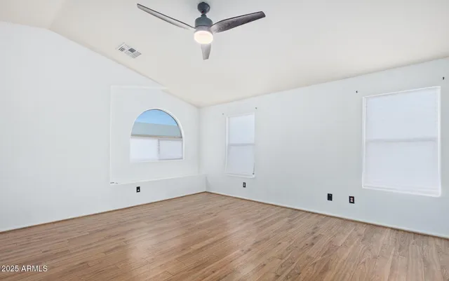 an empty room with a ceiling fan and wooden floor