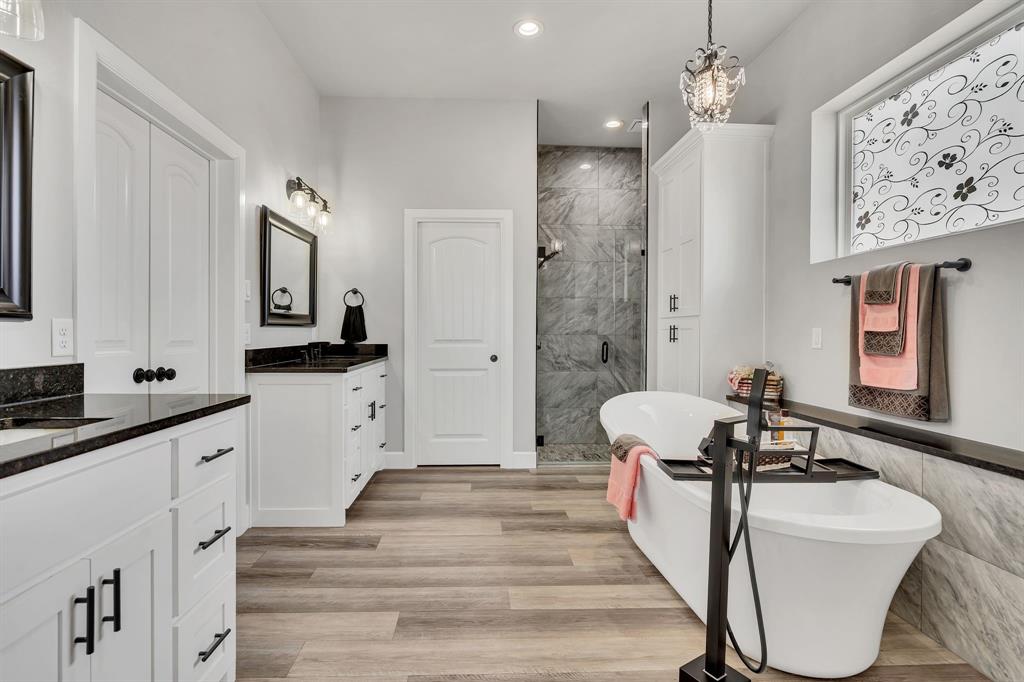 7739 Borth Road Sanger, TX 76266 - Photo 16 of 39 Full bath with a marble finish shower, two vanities, a freestanding tub, light wood-type flooring, and hanging lights