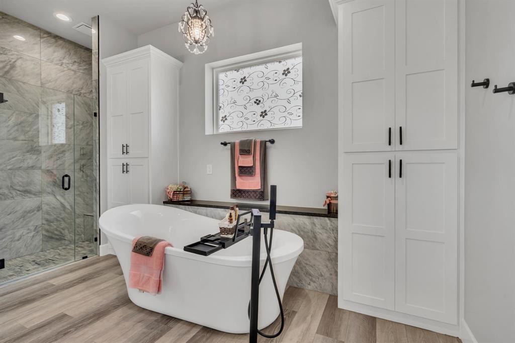 7739 Borth Road Sanger, TX 76266 - Photo 18 of 39 Full bathroom featuring a shower stall, light wood finished floors, a freestanding tub, hanging lights, and tile walls