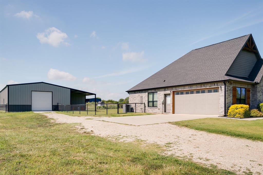 7739 Borth Road Sanger, TX 76266 - Photo 27 of 39 View of property exterior featuring an outbuilding, a detached garage, driveway, roof with shingles, and brick siding