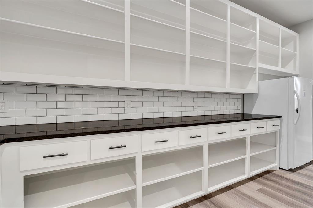 7739 Borth Road Sanger, TX 76266 - Photo 10 of 39 Walk through pantry from garage/mud room to kitchen. Space for dual refrigerators and a dedicated water line if needed. Backsplash, light wood-style floors, white cabinets, and open shelves