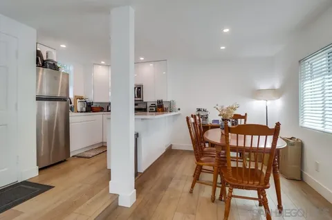 a kitchen with stainless steel appliances a dining table chairs refrigerator and sink