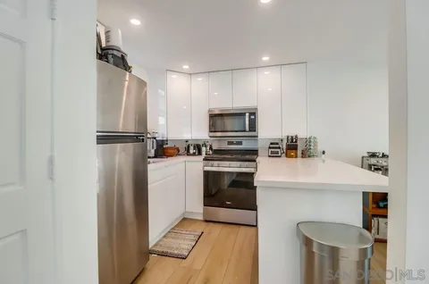 a kitchen with a refrigerator a stove top oven a sink dishwasher and white cabinets with wooden floor