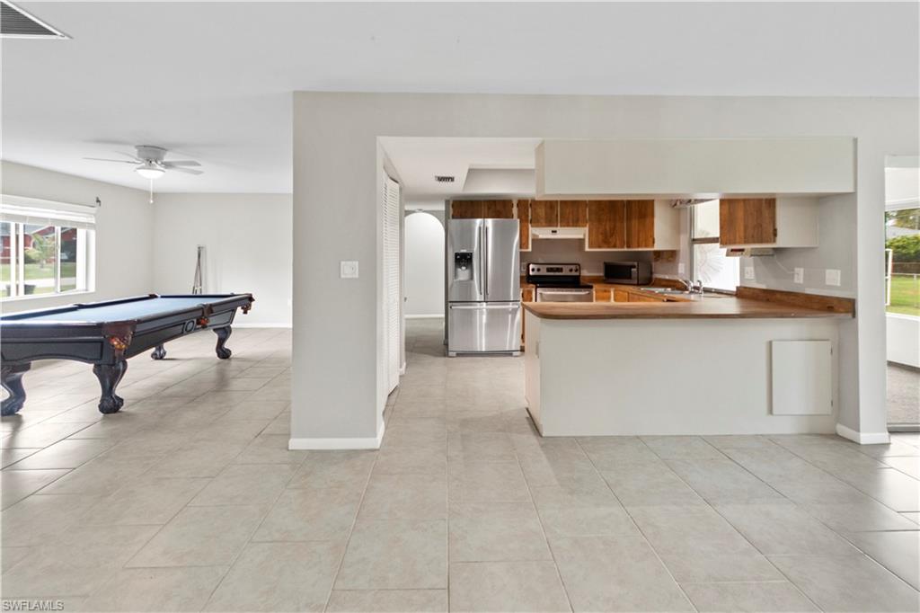 9081 Shaddock Road West Fort Myers, FL 33967 - Photo 5 of 23 a kitchen with stainless steel appliances kitchen island granite countertop a refrigerator and a stove top oven