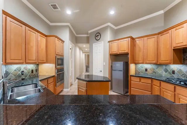 a kitchen with stainless steel appliances granite countertop a refrigerator a stove and a sink with granite countertops