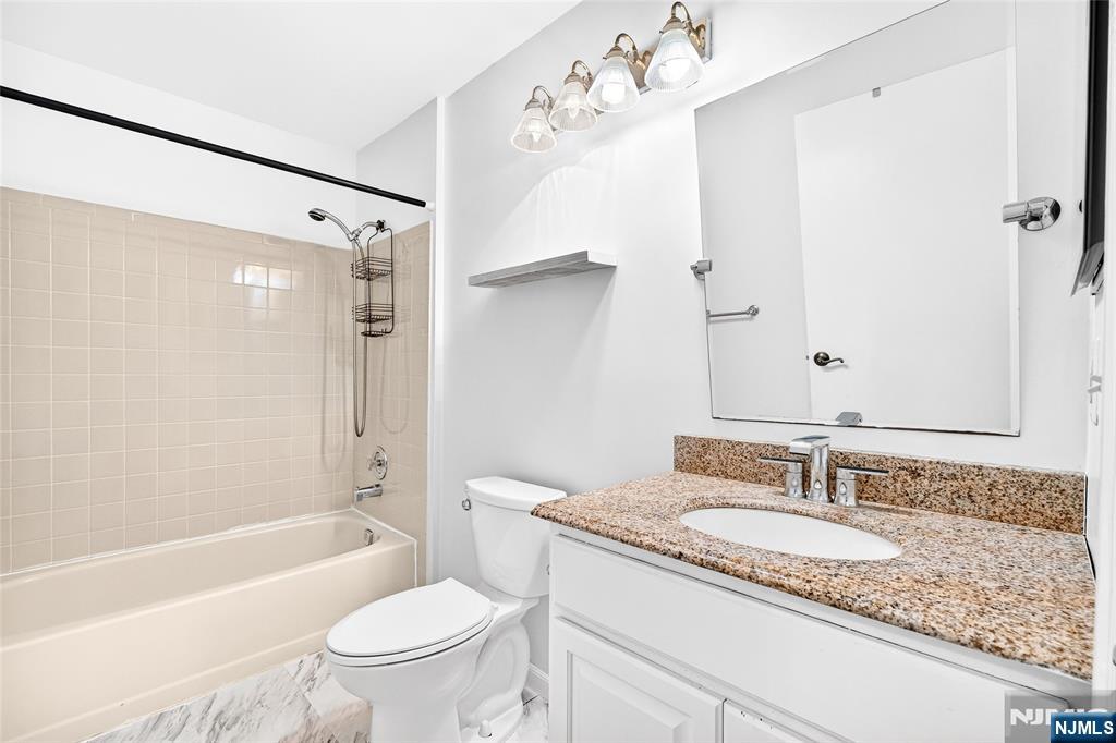 556 Holly Court Mahwah, NJ 07430 - Photo 37 of 46 a bathroom with a granite countertop sink a toilet a mirror a bathtub and shower