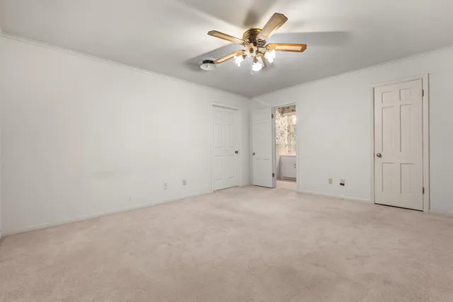 an empty room with a chandelier fan and windows
