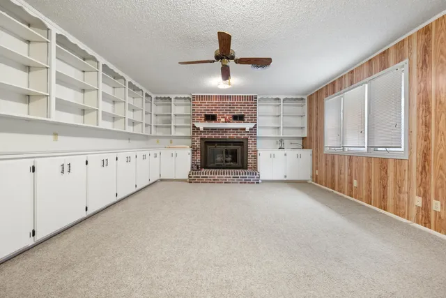 a view of an empty room with a fireplace and window