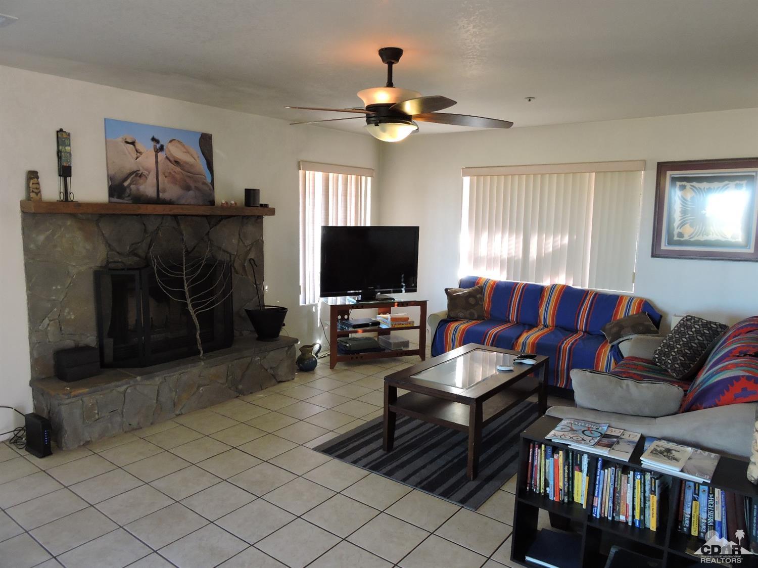 7369 Sunset Road Joshua Tree, CA 92252 - Photo 11 of 37 a living room with furniture a flat screen tv and a fireplace