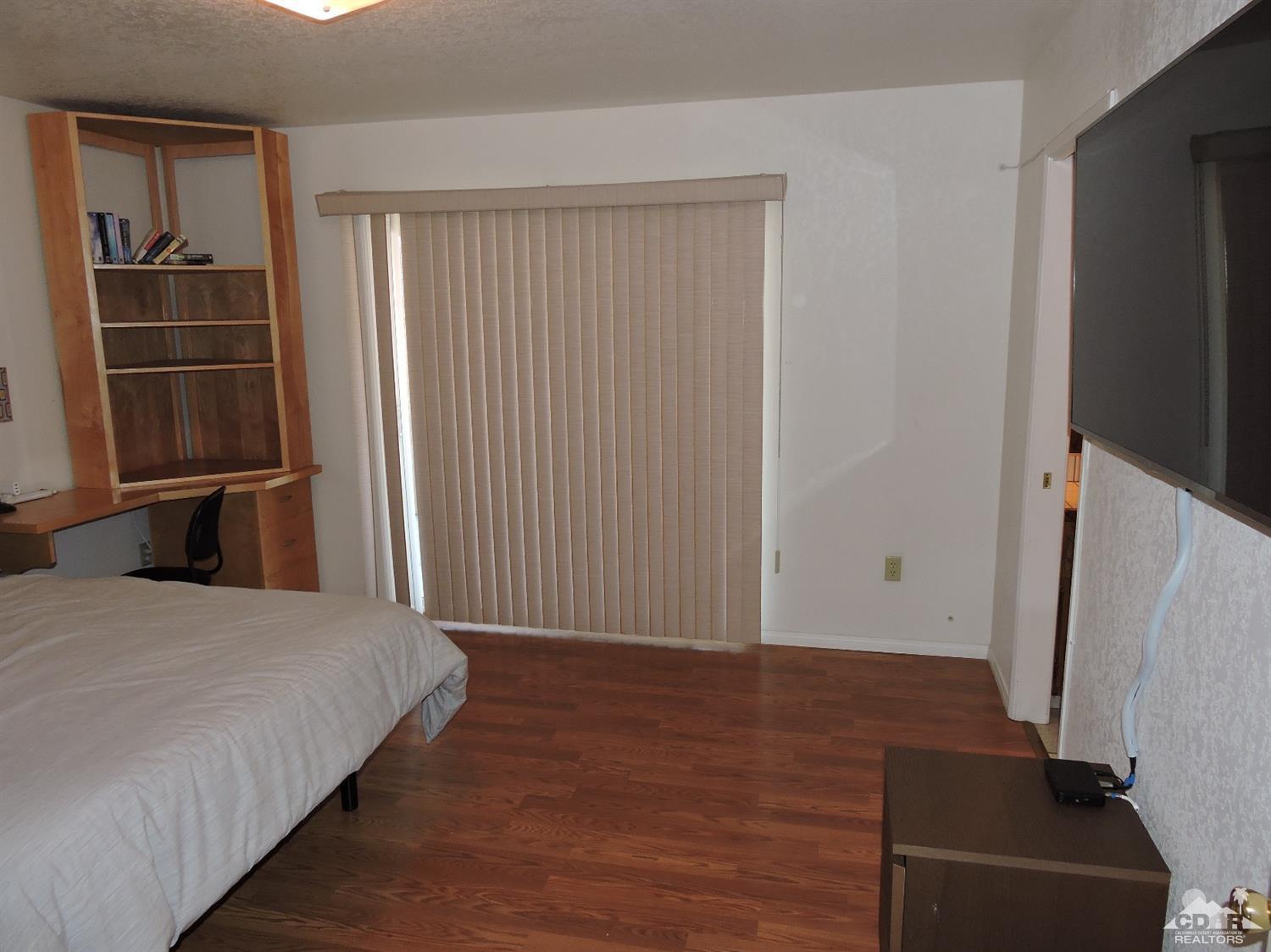 7369 Sunset Road Joshua Tree, CA 92252 - Photo 18 of 37 a bedroom with a bed and a flat tv screen on wall
