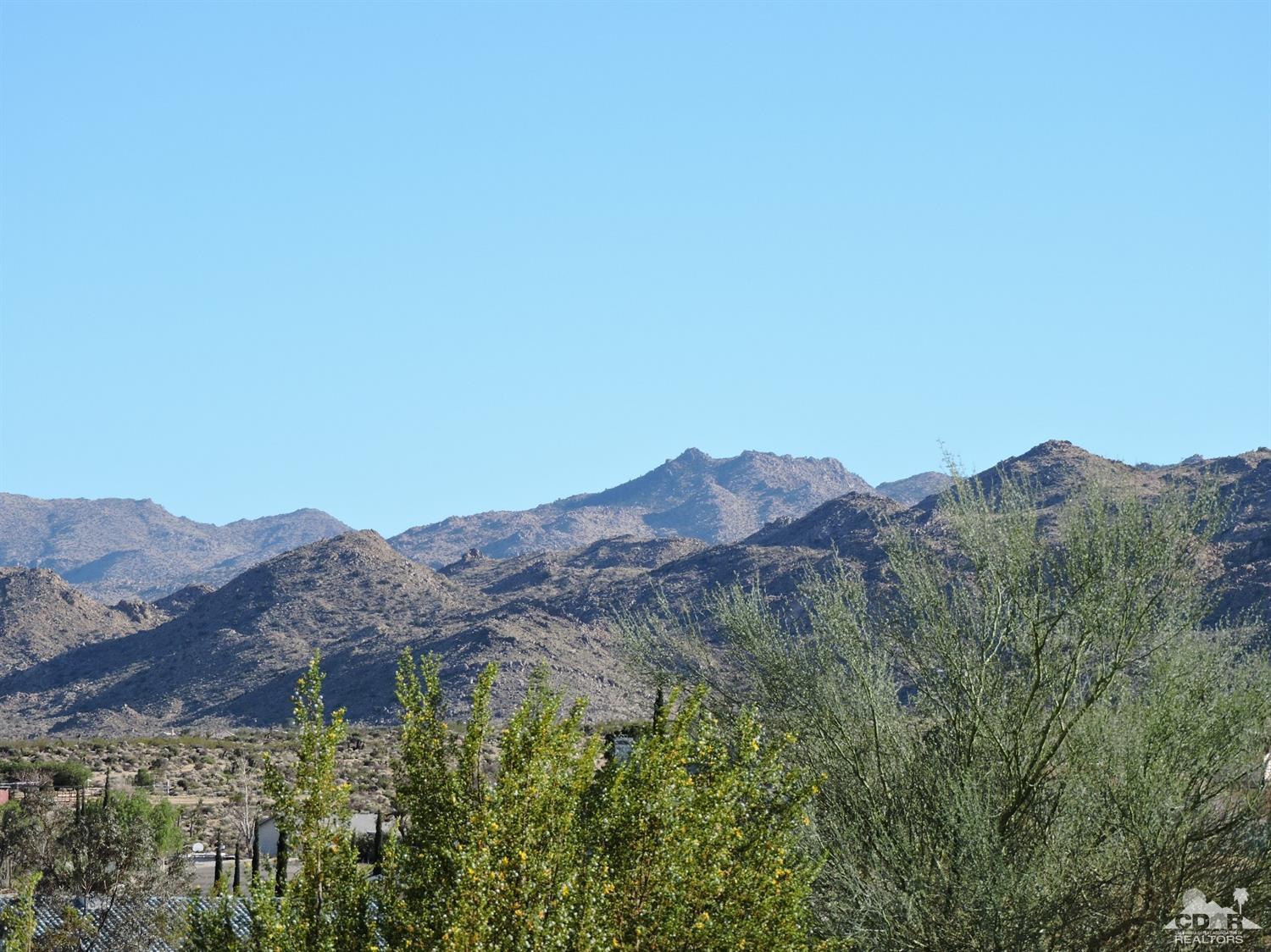 7369 Sunset Road Joshua Tree, CA 92252 - Photo 6 of 37 a view of a lush green field with mountains in the background