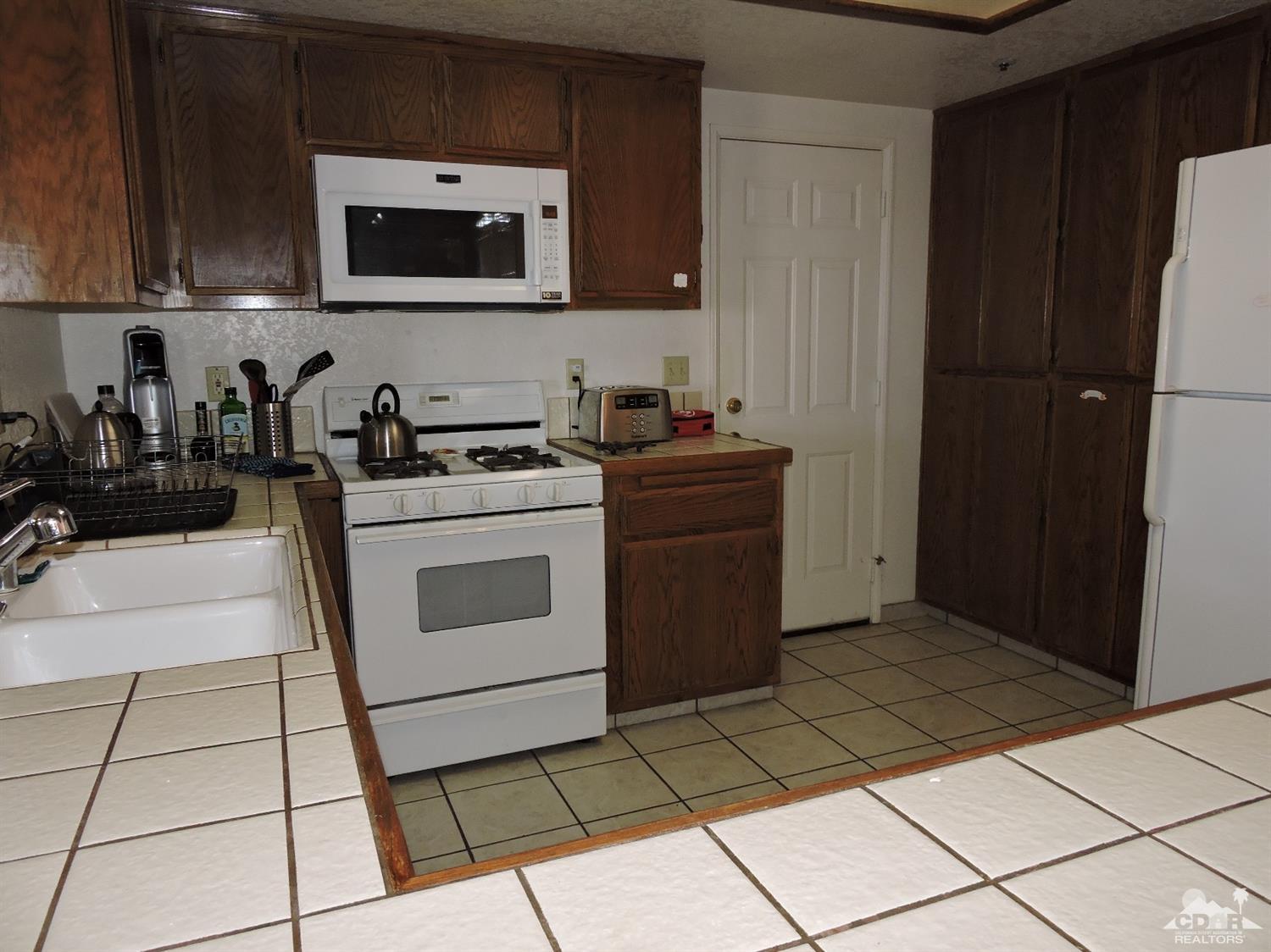 7369 Sunset Road Joshua Tree, CA 92252 - Photo 10 of 37 a kitchen with a stove a microwave and cabinets