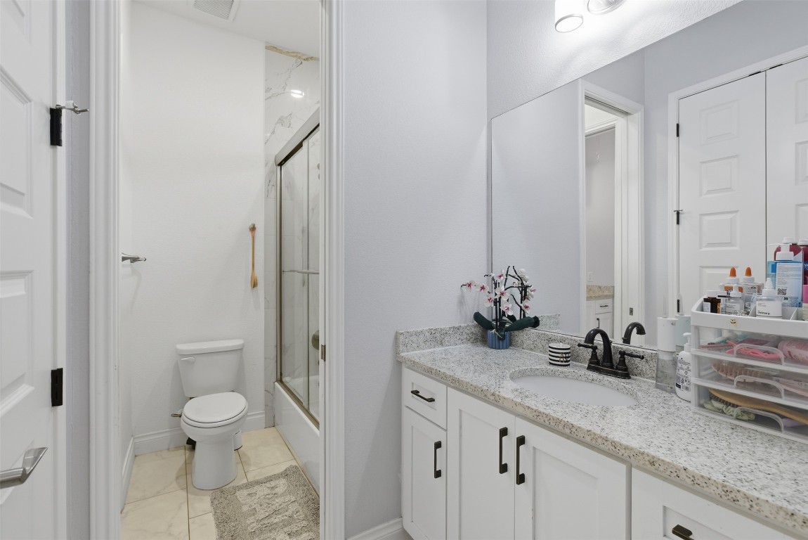 1905 South College Street Georgetown, TX 78626 - Photo 28 of 37 a bathroom with a granite countertop sink a toilet and a mirror
