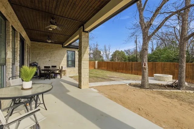a view of a patio with a dining table and chairs with wooden floor and fence