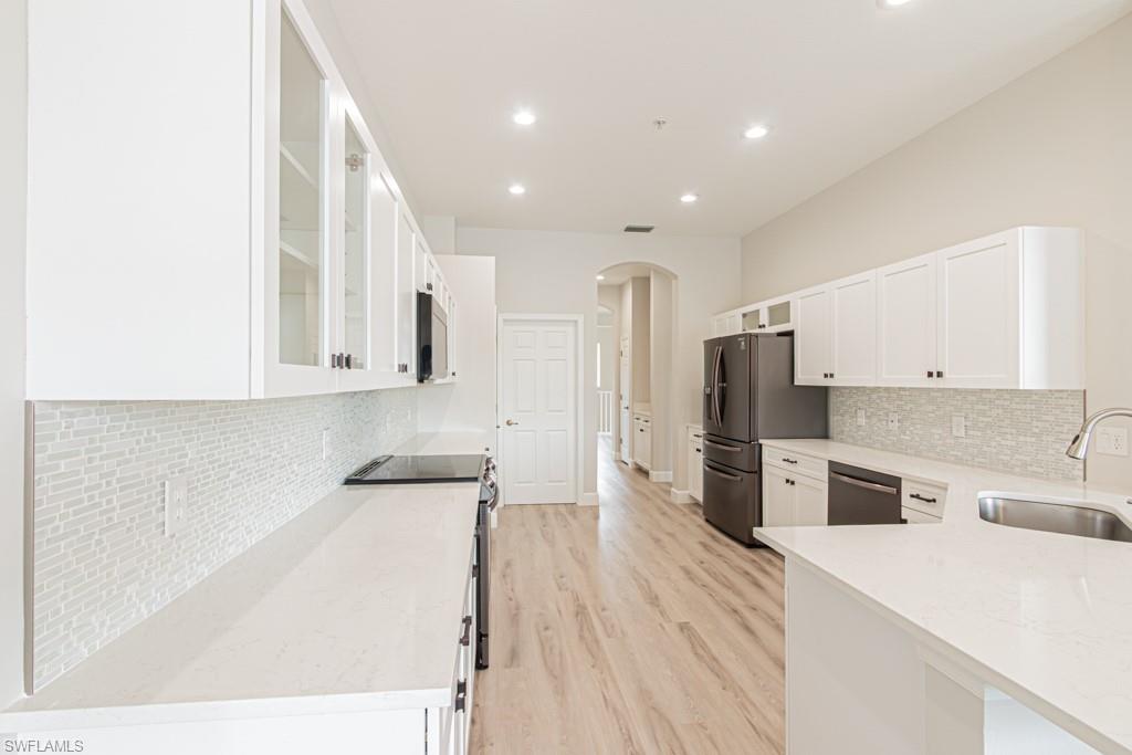 26448 Lucky Stone Road, Unit 202 Bonita Springs, FL 34135 - Photo 17 of 50 a kitchen with stainless steel appliances kitchen island granite countertop a refrigerator oven a sink dishwasher and white cabinets with wooden floor