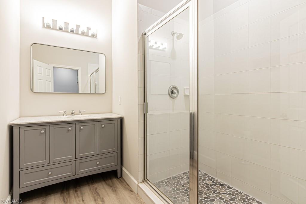 26448 Lucky Stone Road, Unit 202 Bonita Springs, FL 34135 - Photo 39 of 50 a bathroom with a sink a mirror and shower