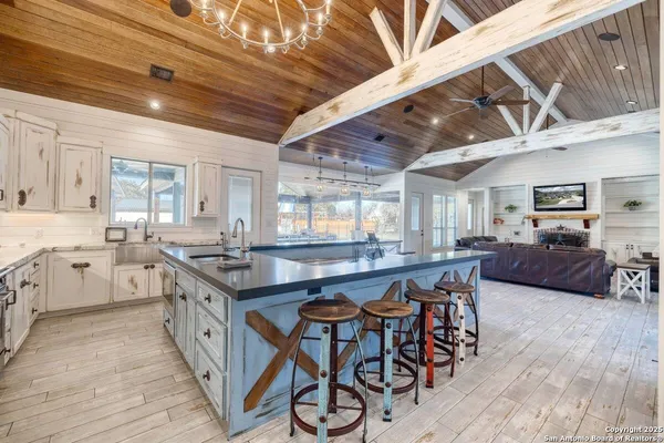 a kitchen with stainless steel appliances a stove a sink dishwasher a dining table and chairs with wooden floor